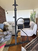 Front angle view of the black wrought iron sign holder showing the pointed finial on top and scrollwork support.