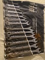 Photo of 17 piece combination wrench set arranged in a black fabric roll-up pouch, showing the wrenches in individual pockets; some plastic remains on handles.