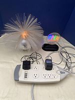 Fiber optic bar light, "OPEN" sign, and power strip with cords and adapters shown together on a surface