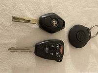 Top view of BMW key fob and black multi-button key fob showing buttons and metal keys