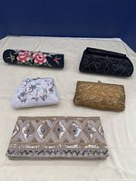 All five beaded purses placed on a cream cloth background, showing each purse's size and overall look.