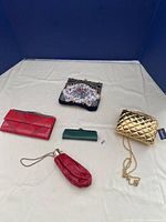 Five vintage small purses displayed on white surface in blue-lined box, showing variety and size differences