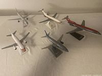 Five small scale model airplanes displayed together showing varied airline liveries and display stands