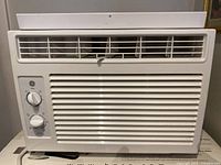 Front view of GE small room air conditioner with control knobs and vents visible.