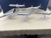 Lot of 5 scale model airplanes from different airlines on display, with stands