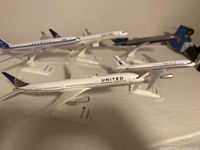 Photo showing four scale model airplanes featuring United Airlines liveries in varying aircraft models on stands.