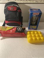 Full lot shot including black and red portable cooler, Fireside Supreme firelog package, Coleman LED lantern box, and yellow plastic egg case