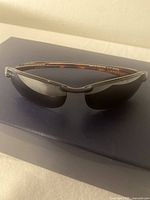 Side angle showing brown tinted lenses, semi-rimless frame, and part of tortoiseshell arms.