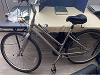 Full side view of silver Specialized cruiser bicycle showing frame, wheels, pedals, handlebars, and padded seat cover.