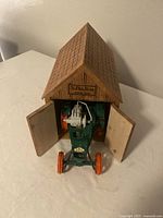 Wooden barn with doors open displaying the green and orange metal tractor inside.