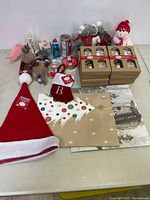Wide view of various Christmas decorations, bags, ribbons, and tags spread on table with Santa hat prominently visible.