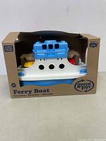 Front and top view of Green Toys ferry boat toy in original packaging, showing white and blue ferry boat with circular windows and labeled as made in the USA from recycled plastic.