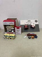 Photo showing all Christmas ornaments including boxed Griswold's House ornament, boxed Moose Mug, scooter ornaments on card, yellow bus, and small vehicle ornaments.