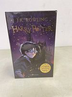 Boxed set of Harry Potter book 1 showing cover with Harry in front of Hogwarts illustration in purple tones.