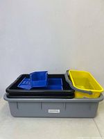 Bins stacked inside each other showing the gray base, black bins, yellow caddy and blue small bins on top.