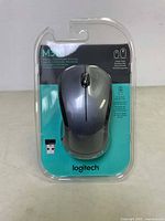 Front view of Logitech M310 wireless mouse in clear plastic retail packaging showing mouse and USB wireless receiver.