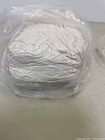 Photo of a large block of white air dry clay wrapped in plastic on a flat surface