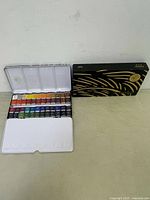 Open metal folding case showing 36 solid watercolor pigment pans arranged in rows.
