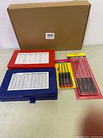 Two plastic cases and two packages of pick and hook tools laid out on a flat surface