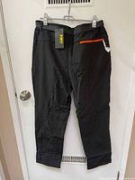 Front and back view of black insulated snow pants with orange zipper pocket and belt