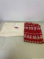 Folded cream-colored long sleeve pajama top and folded red holiday patterned pajama pants.