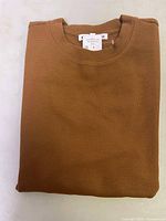 Folded brown waffle knit sweater showing front and crew neck collar.