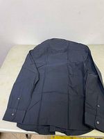 Dark colored men's long sleeve shirt showing the back side laid flat.