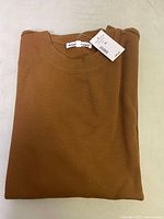 Folded brown waffle knit men's sweater with a visible Bootlegger tag and price tag attached.