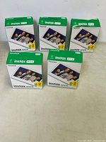 Front view showing five boxed sets of Fujifilm Instax Wide film with packaging displaying sample images and exposure count.