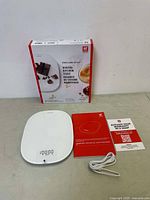 White Zwilling Enfinigy digital kitchen scale with digital display, USB charging cable, user manual, and original product box.