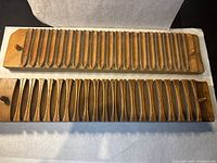 Top view of two wooden cigar molds placed side by side, showing multiple cavities for cigar shaping.