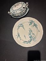 Gravy boat with lid and bamboo patterned dinner plate on black background