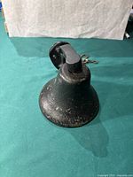 Front view of black metal wall-mounted bell showing the bell body and mounting bracket.
