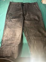 Front view of black leather pants showing smooth texture and straight legs.