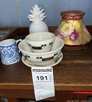 Wide shot showing Sterling China bowls and plate with geometric bird designs, hand painted floral porcelain vase, blue and white mug, and white ceramic pineapple decor.