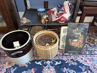 Photo of lot showing ceramic crock, wood and ceramic planter, American flag cloth, wicker basket, bell, and two welcome signs on patterned rug.