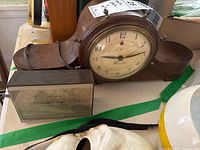 General Electric Ships Bell mantle clock in wooden curved case with clock face showing Arabic numbers and hour, minute hands.
