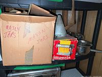 Cardboard box labeled 'Mason Jars' containing Ball Mason jars alongside a boxed Imperia pasta machine and metal food mills