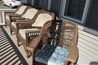 Four brown rattan wicker chairs lined up on front porch