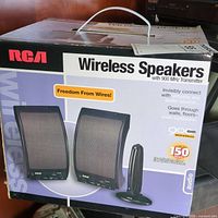 Original packaging box for RCA Wireless Speakers with images of two speakers and transmitter, highlighting wireless features and range.