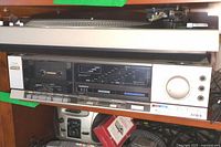 Aiwa stereo cassette deck front panel showing cassette compartment, tuner display, controls and large volume knob.