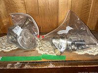 Two zip-top bags containing disassembled sterling silver candlestick pieces on wooden surface