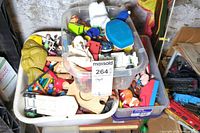 Top view of two clear plastic storage bins filled with assorted plastic toys including vehicles, figurines, and puzzle pieces.