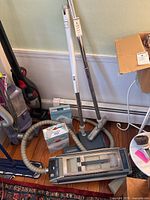 Electrolux Ultralux vacuum cleaner with hose, wand extensions, vacuum head and opened boxes of vacuum bags on floor.
