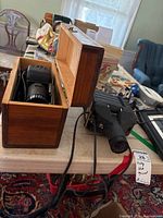Two vintage slide projectors on a table, one in a wooden box (Skan SP-100) and one next to it (Argus)