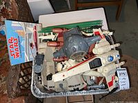 Vintage Star Wars toy vehicles and a book are arranged on a table featuring a Rebel Snowspeeder and the Empire Strikes Back book