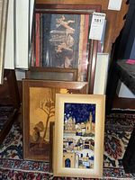 Framed ceramic tile wall art and three additional framed wood art pieces grouped on floor against wall, showing overall lot contents and framing styles.