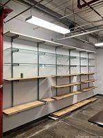 Full view of large wall-mounted shelving system with multiple wooden and glass shelves spanning 15.5 feet wide and 8 feet tall, showing metal vertical tracks and brackets.