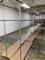 Long rows of Metro chrome wire shelving frames assembled in warehouse, wooden shelves on floor below.