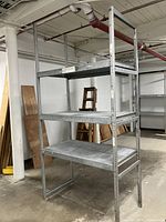 Full view of assembled metal shelving unit with three shelves in industrial setting.